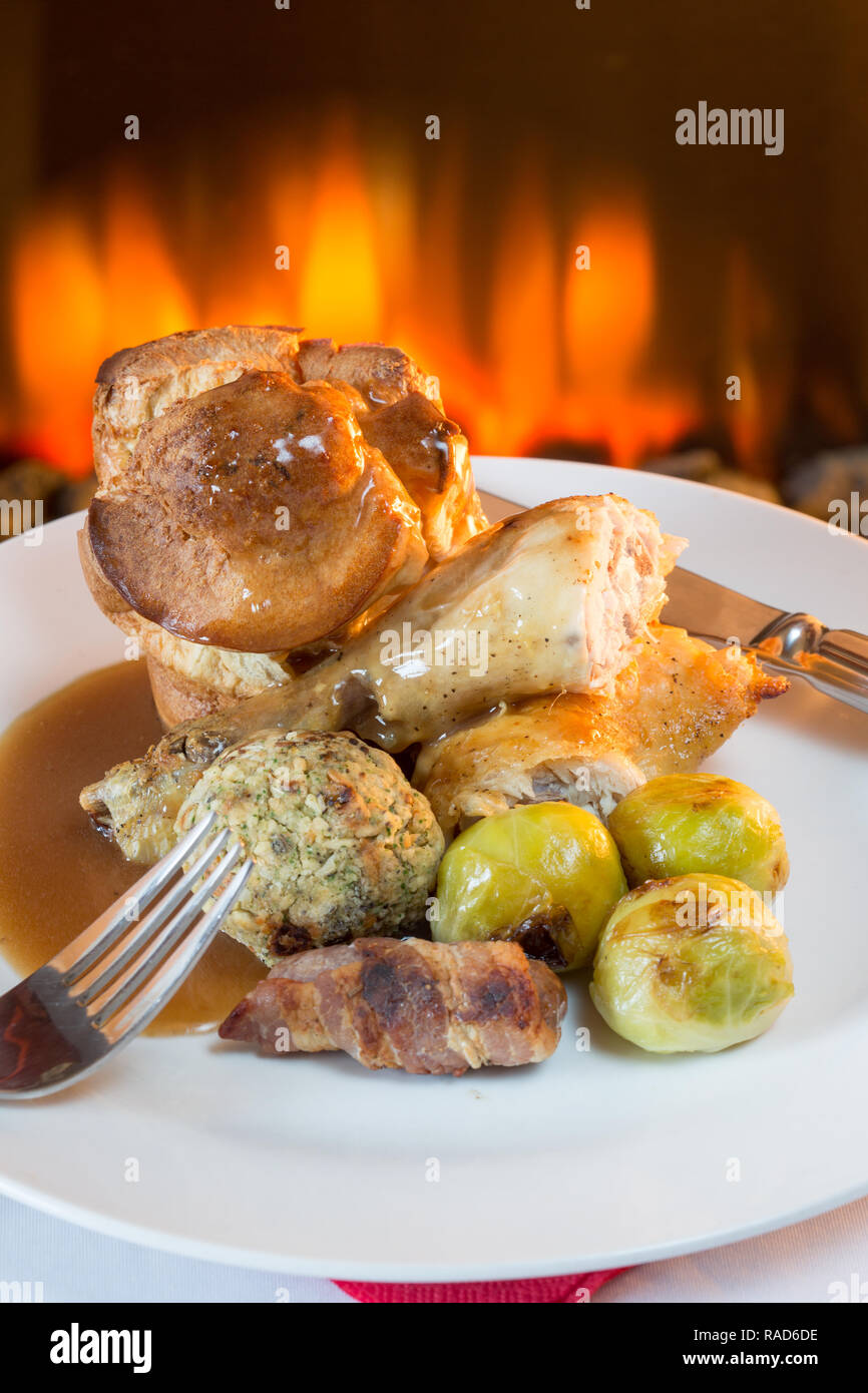 A popular British roast Chicken Sunday dinner with Yorkshire pudding, Stuffing, Pigs in blankets and potato and vegetables. Stock Photo