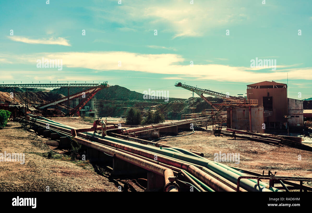 Complex of mine buildings of a old mining enterprise with mineral conveyor belt and and pipes for the extraction of gold and cooper, with the blue sky Stock Photo