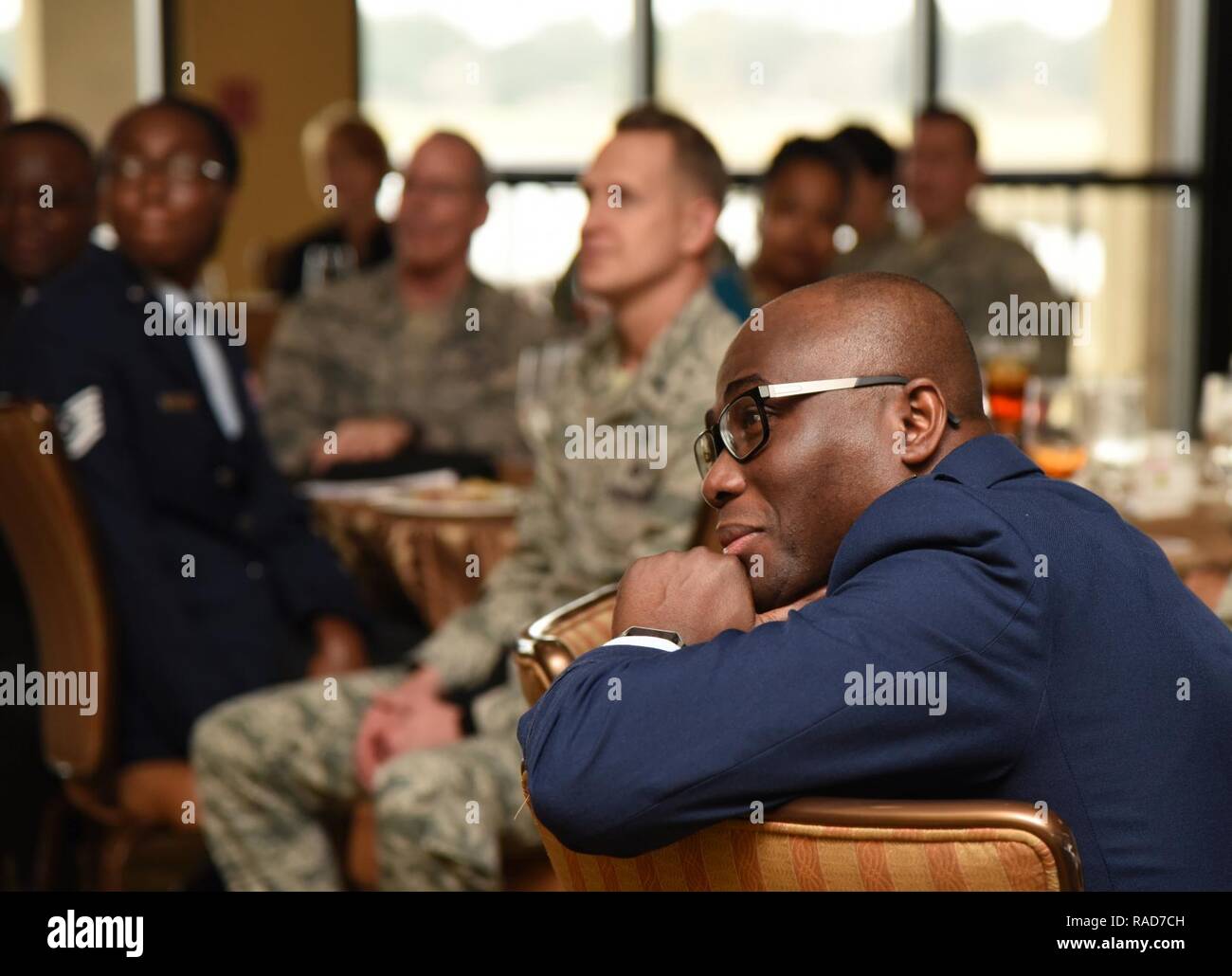 Chaplain (Capt.) Eugene Ansah, 81st Training Wing chaplain, listens to the message of  Rev. Eric Dickey, First Missionary Baptist Church pastor and event speaker, during the annual Dr. Martin Luther King Jr. Memorial Luncheon at the Bay Breeze Event Center, Jan. 17, 2017, on Keesler Air Force Base, Miss. The Keesler African-American Heritage Committee sponsored event honored King’s legacy and his efforts to inspire civil rights activism within the African-American community. Stock Photo