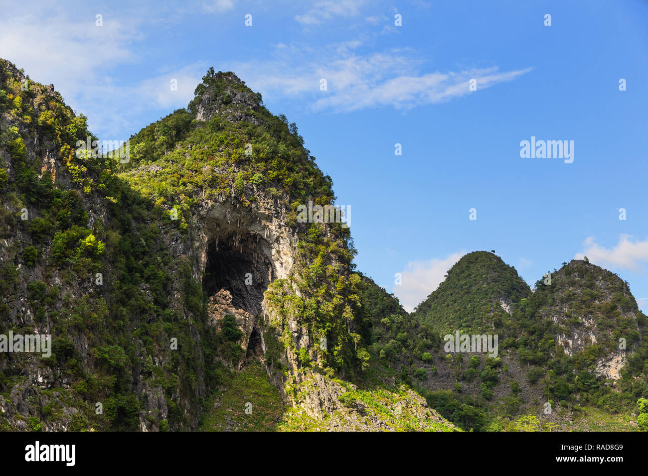 Tall green mountain peak and limestone cave entrance in Ma Pi Long pass, Ha Giang Loop, Ha Giang Province, Vietnam, Asia Stock Photo
