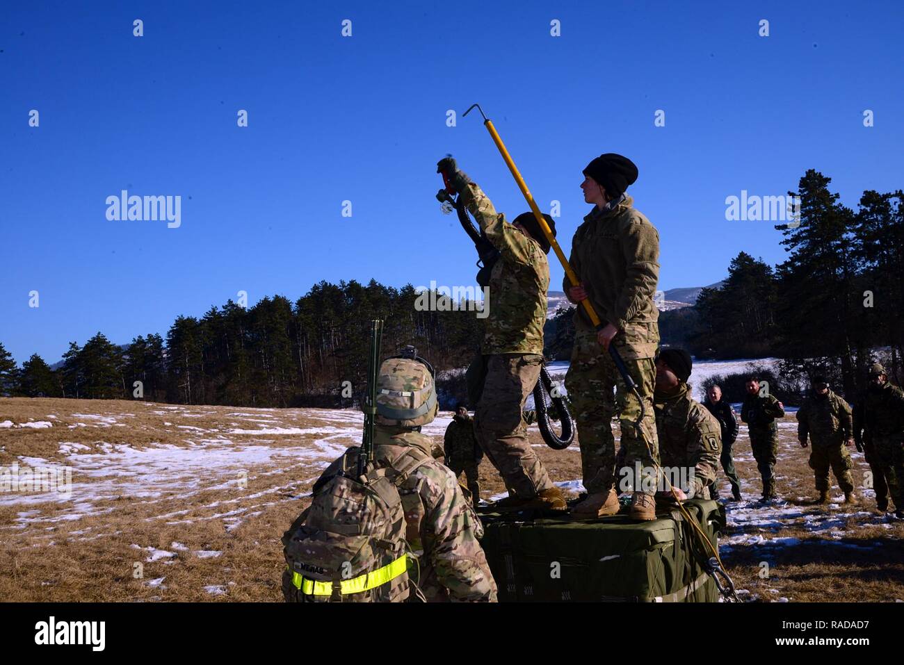 U.S. Army paratroopers from the 173rd Brigade Support Battalion, 173rd Airborne Brigade, along with Slovenian and Italian soldiers conduct a briefing before sling load operations with a Slovenian Air Force Eurocopter H3-74 during exercise Lipizzaner III in Pocek, Slovenia, Jan. 27, 2017. Lipizzaner is a combined squad-level training exercise in preparation for platoon evaluation, and to validate battalion-level deployment procedures. Stock Photo
