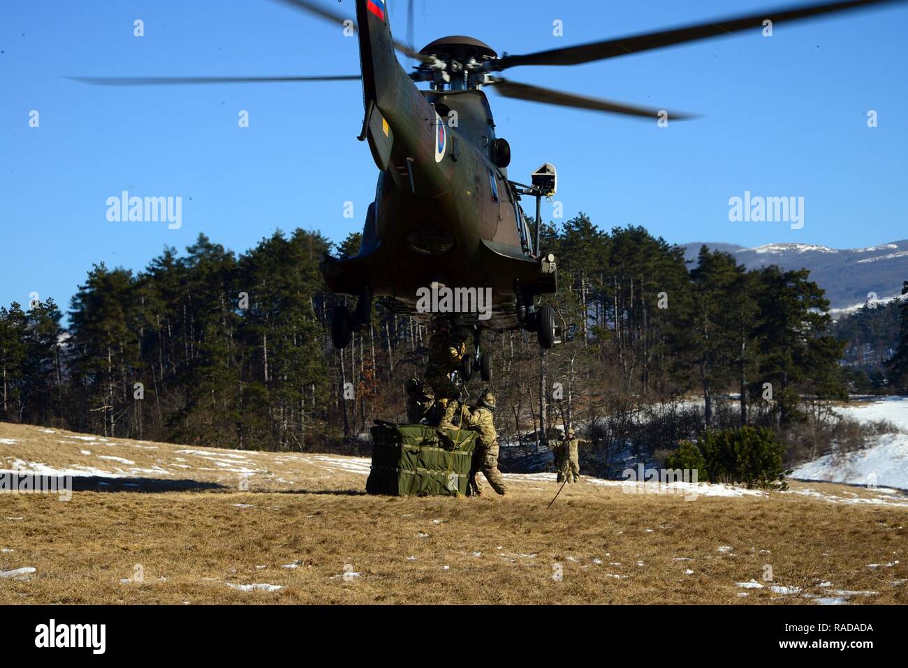 U.S. Army paratroopers from the 173rd Brigade Support Battalion, 173rd Airborne Brigade, together with Slovenian and Italian soldiers conduct sling load operations using a Slovenian Air Force Eurocopter H3-74 during exercise Lipizzaner III in Pocek, Slovenia, Jan. 27, 2017. Lipizzaner is a combined squad-level training exercise in preparation for platoon evaluation, and to validate battalion-level deployment procedures. Stock Photo