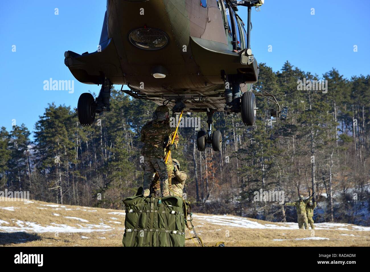 U.S. Army paratroopers from the 173rd Brigade Support Battalion, 173rd Airborne Brigade, together with Slovenian and Italian soldiers conduct sling load operations using a Slovenian Air Force Eurocopter H3-74 during exercise Lipizzaner III in Pocek, Slovenia, Jan. 27, 2017. Lipizzaner is a combined squad-level training exercise in preparation for platoon evaluation, and to validate battalion-level deployment procedures. Stock Photo