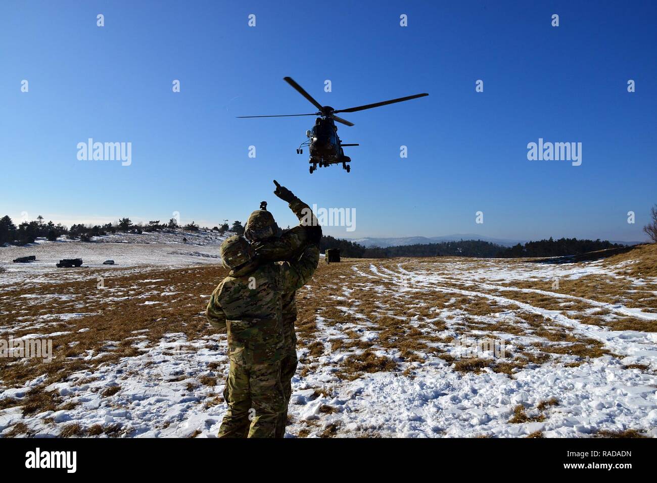 U.S. Army paratroopers from the 173rd Brigade Support Battalion, 173rd Airborne Brigade, signal and direct a Slovenian Air Force Eurocopter H3-74 during sling load operation with during exercise Lipizzaner III in Pocek, Slovenia, Jan. 27, 2017. Lipizzaner is a combined squad-level training exercise in preparation for platoon evaluation, and to validate battalion-level deployment procedures. Stock Photo