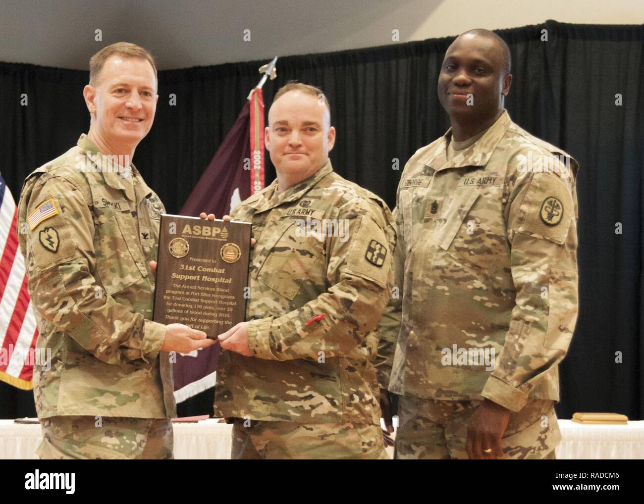 Col. John A. Smyrski III (left), commander, William Beaumont Army Medical Center, and Command Sgt. Maj. Donald George, command sergeant major, WBAMC, present a plaque to a Soldier with the 31st Combat Support Hospital for the unit’s overall blood donations equaling 22 gallons of blood, during the Fort Bliss Blood Donor Center’s annual Blood Donor Recognition Ceremony at the Centennial Banquet and Conference Center, Fort Bliss, Jan. 26. Stock Photo