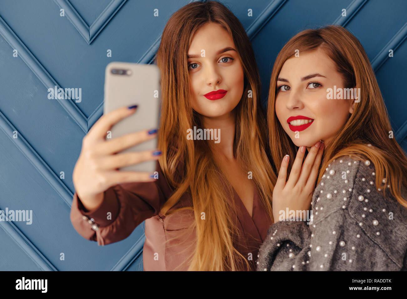 Two Attractive Stylish Young Girls With Smartphones On Simple Aqua