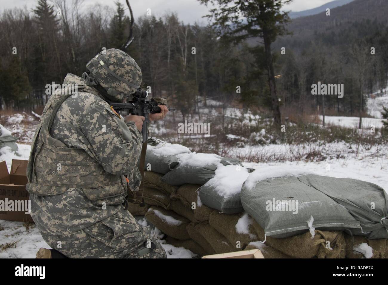 U.S. Army Spc. Emelio Madera-Valerio, assigned to Charlie Company, 3rd Battalion, 172nd Infantry Regiment, 86th Infantry Brigade Combat Team (Mountain), New Hampshire National Guard, provides cover fire for mortar crews at Camp Ethan Allen Training Site, Jericho, Vt., Jan. 26, 2017. The Soldiers repelled a simulate enemy attack in one of the different scenarios for mortar teams during their winter annual training. Stock Photo