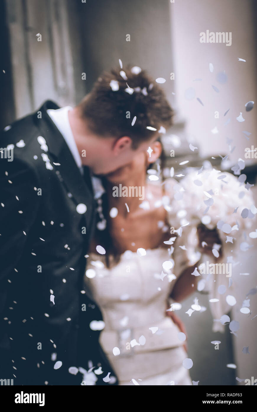 newlyweds they kiss - intentional defocused image - focus on confetti - sensory connections Stock Photo