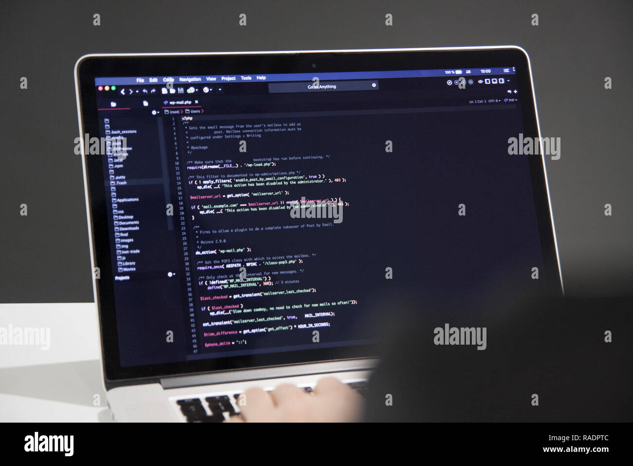 Male programmer working on laptop computer at white desk in office, codding php code Stock Photo