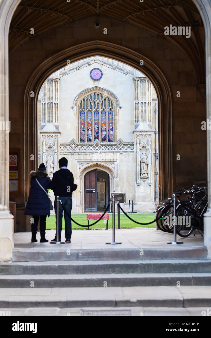 Two tourists view the courtyard and chapel as seen from the covered main entrance to Corpus Christi college, Cambridge university, England. Stock Photo