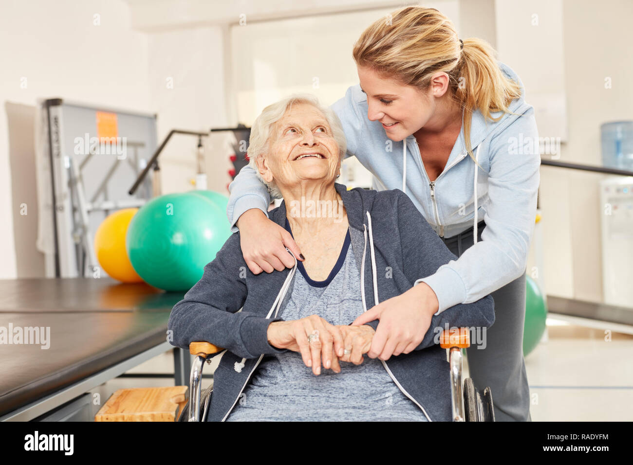 Trainer takes care of disabled senior woman in rehab Stock Photo