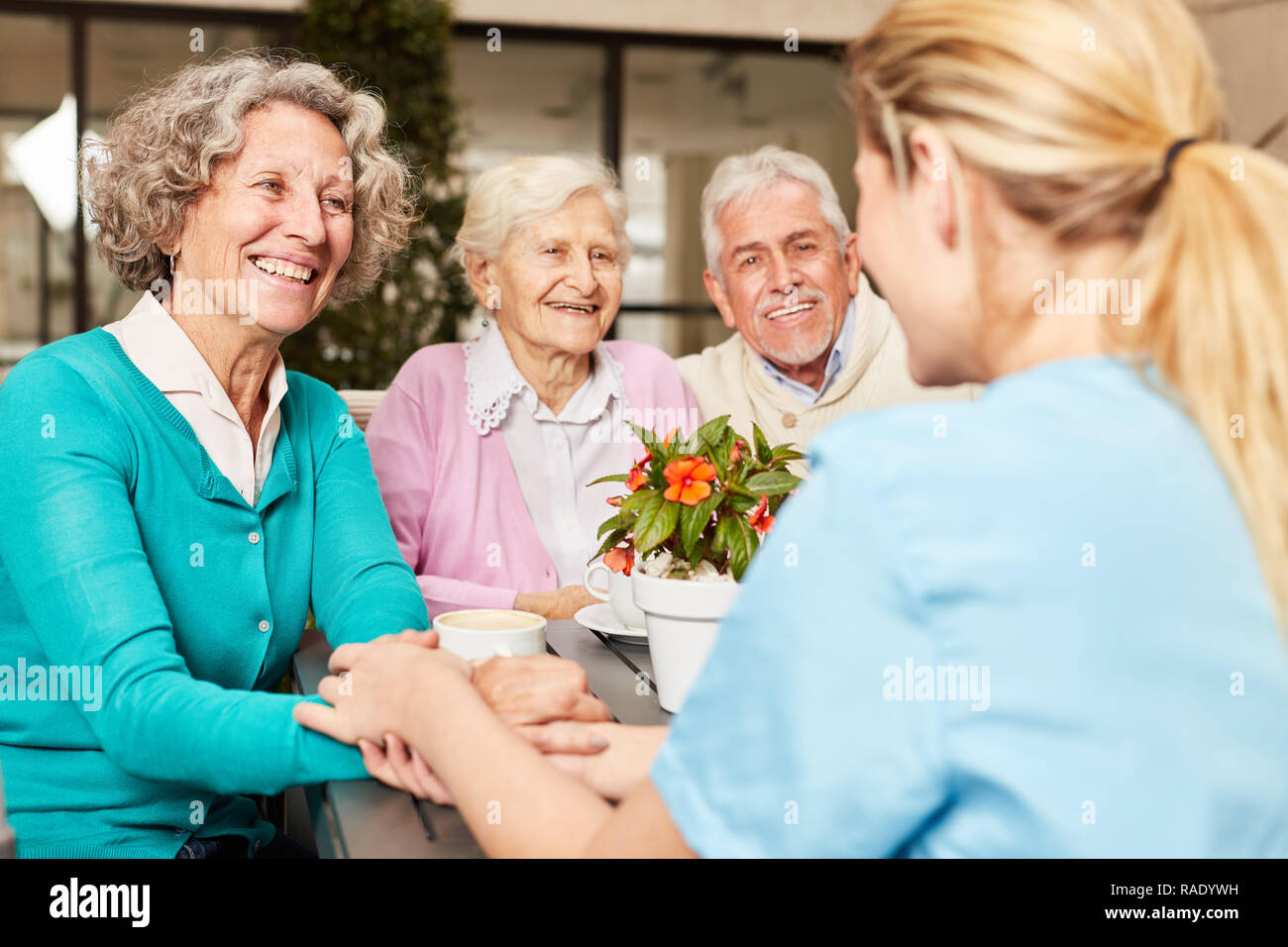Caregiver takes care of a group of happy seniors in the retirement home Stock Photo