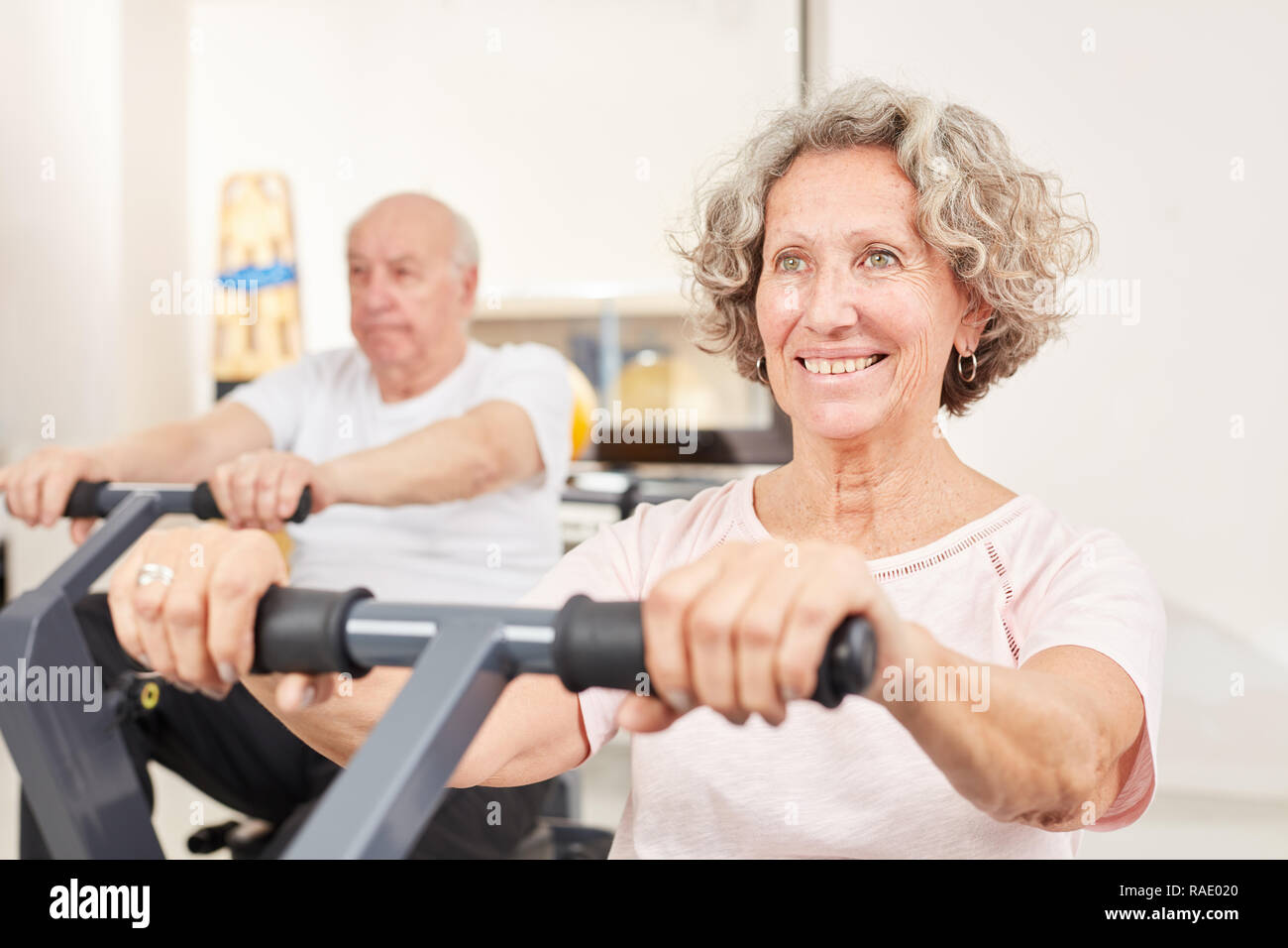 Happy senior woman exercises fitness on the ergometer while ...