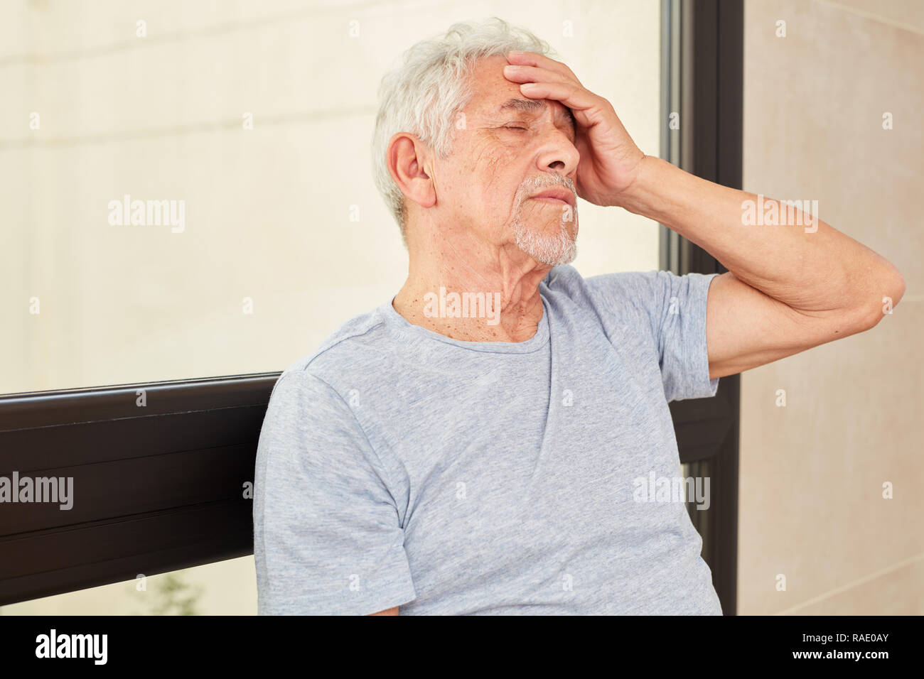 Senior man touches his head as a sign of nausea and dizziness Stock Photo
