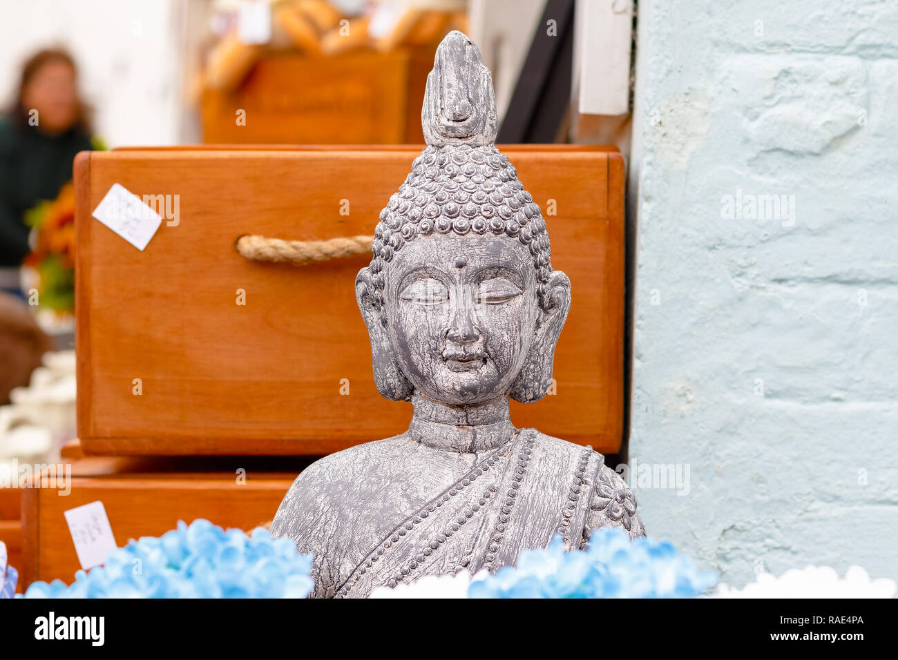 Stone Buddha statue on display for sale at outdoor market of the UK