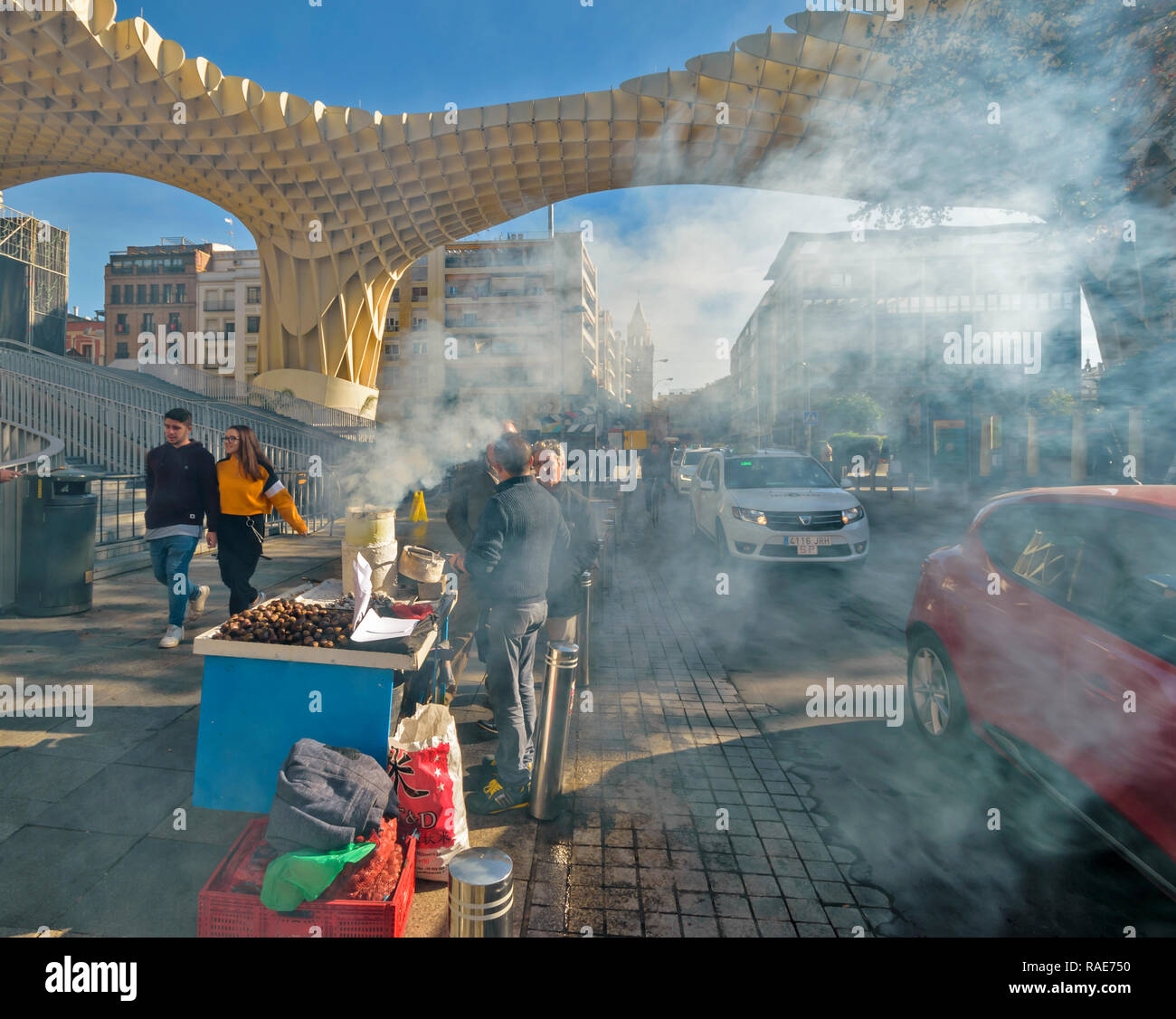 METROPOL PARASOL ENCARNACION SQUARE SEVILLE SPAIN EARLY MORNING SMOKE FROM ROAST CHESTNUT SELLER AND PASSING TRAFFIC Stock Photo