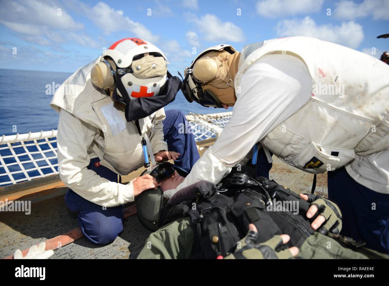 EASTERN PACIFIC OCEAN – Seaman Kristine Kearny (left), a crewmember aboard the Coast Guard Cutter Sherman, removes Lt. Sean O’Dowd’s helmet on Sherman’s flight deck during a helicopter-crash-on-deck drill, Jan. 19, 2017. The crew of Sherman is currently deployed in support of counter drug operations. Cutters like Sherman routinely conduct operations from South America to the Bering Sea conducting alien migrant interdiction operations, domestic fisheries protection, search and rescue, counter-narcotics and other Coast Guard missions at great distances from shore keeping threats far from the U.S Stock Photo