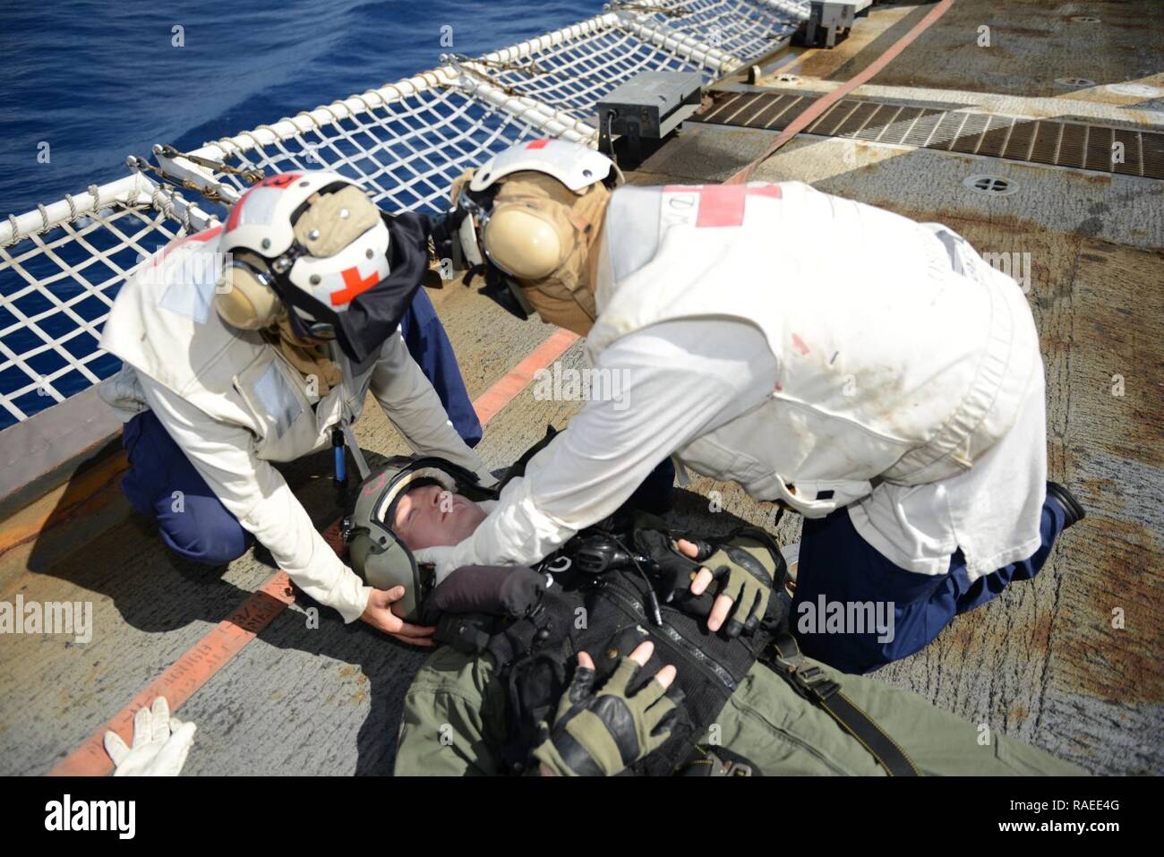 EASTERN PACIFIC OCEAN – Seaman Kristine Kearny (left), a crewmember aboard the Coast Guard Cutter Sherman, removes Lt. Sean O’Dowd’s helmet on Sherman’s flight deck during a helicopter-crash-on-deck drill, Jan. 19, 2017. The crew of Sherman is currently deployed in support of counter drug operations. Cutters like Sherman routinely conduct operations from South America to the Bering Sea conducting alien migrant interdiction operations, domestic fisheries protection, search and rescue, counter-narcotics and other Coast Guard missions at great distances from shore keeping threats far from the U.S Stock Photo
