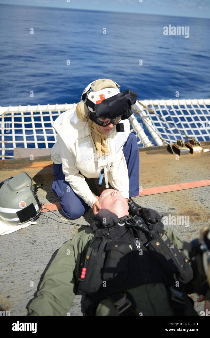 EASTERN PACIFIC OCEAN – Seaman Kristine Kearny (upper), a crewmember aboard the Coast Guard Cutter Sherman, holds Lt. Sean O’Dowd’s head in c-spine on Sherman’s flight deck during a helicopter-crash-on-deck drill, Jan. 19, 2017. The crew of Sherman is currently deployed in support of counter drug operations. Cutters like Sherman routinely conduct operations from South America to the Bering Sea conducting alien migrant interdiction operations, domestic fisheries protection, search and rescue, counter-narcotics and other Coast Guard missions at great distances from shore keeping threats far from Stock Photo