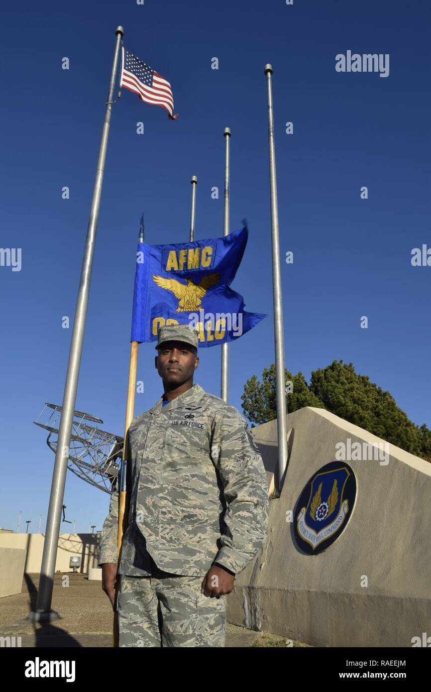 Master Sgt. Teodros Rembert, Oklahoma City Air Logistics Complex first sgt., stands near the base flag pole with the unit guidon prior to an official retreat ceremony Jan. 24, 2017, Tinker Air Force Base, Oklahoma. OC-ALC is an Air Force Materiel Command unit as noted at the top of the guidon as well as the AFMC badge featured on the wall behind. Stock Photo