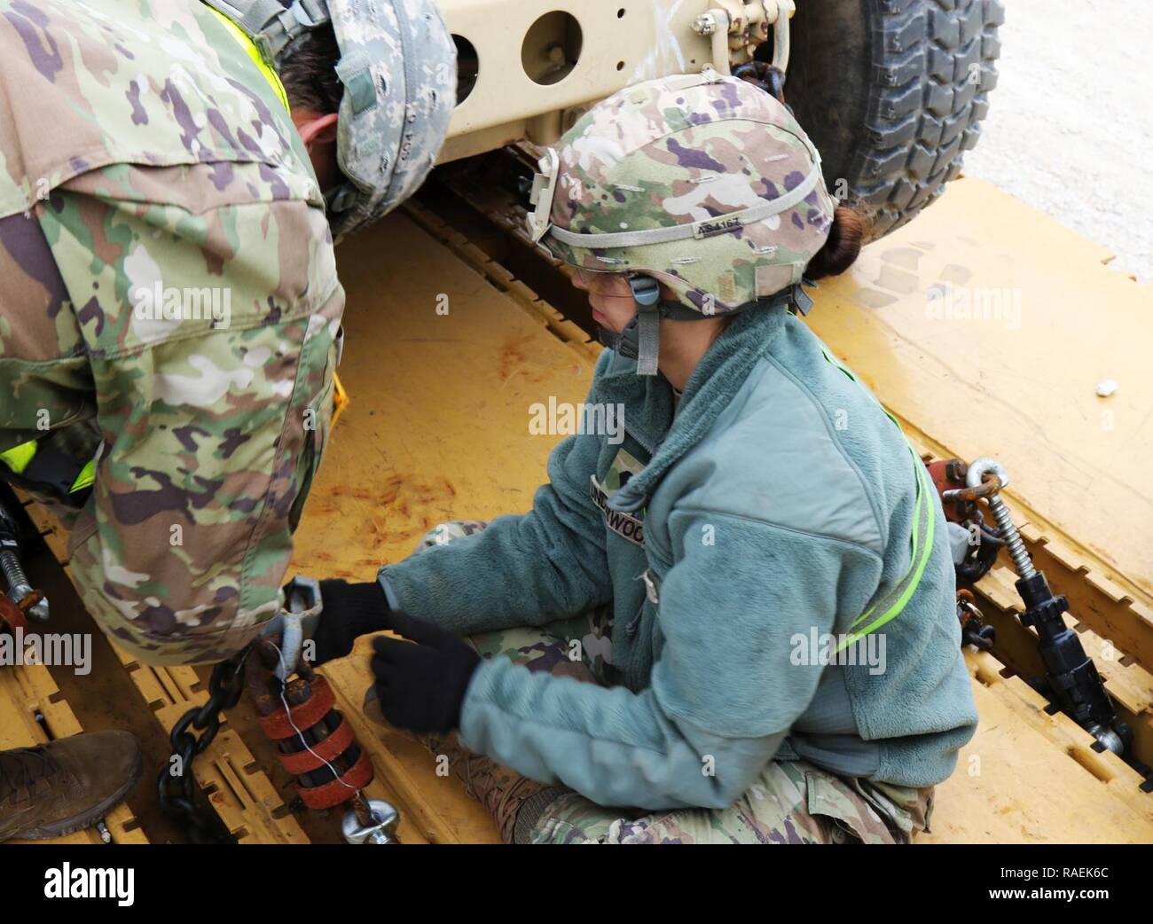 Sgt. Velez, left, and Spc. Underwood, 303rd Military Intelligence Battalion, 504th Military Intelligence Brigade, tie down a vehicle, Dec. 12, 2018, Fort Hood, Texas. They were assisting with rail load operations. Stock Photo