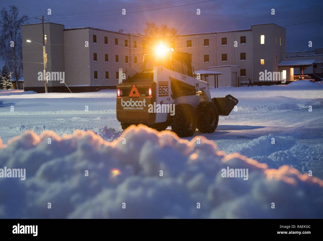 An Arctic Warrior operates a bobcat to remove snow after the first