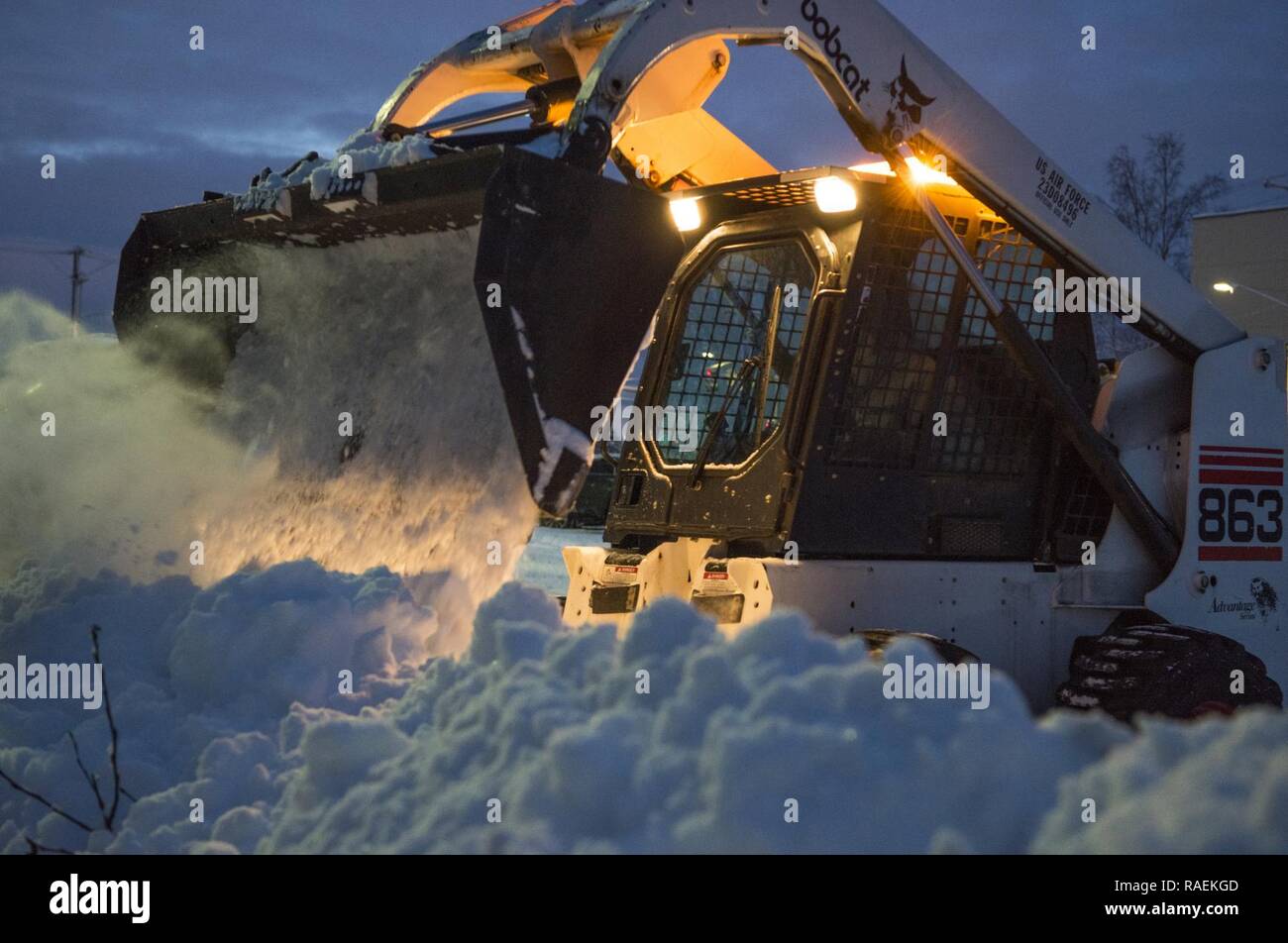 An Arctic Warrior operates a bobcat to remove snow after the first