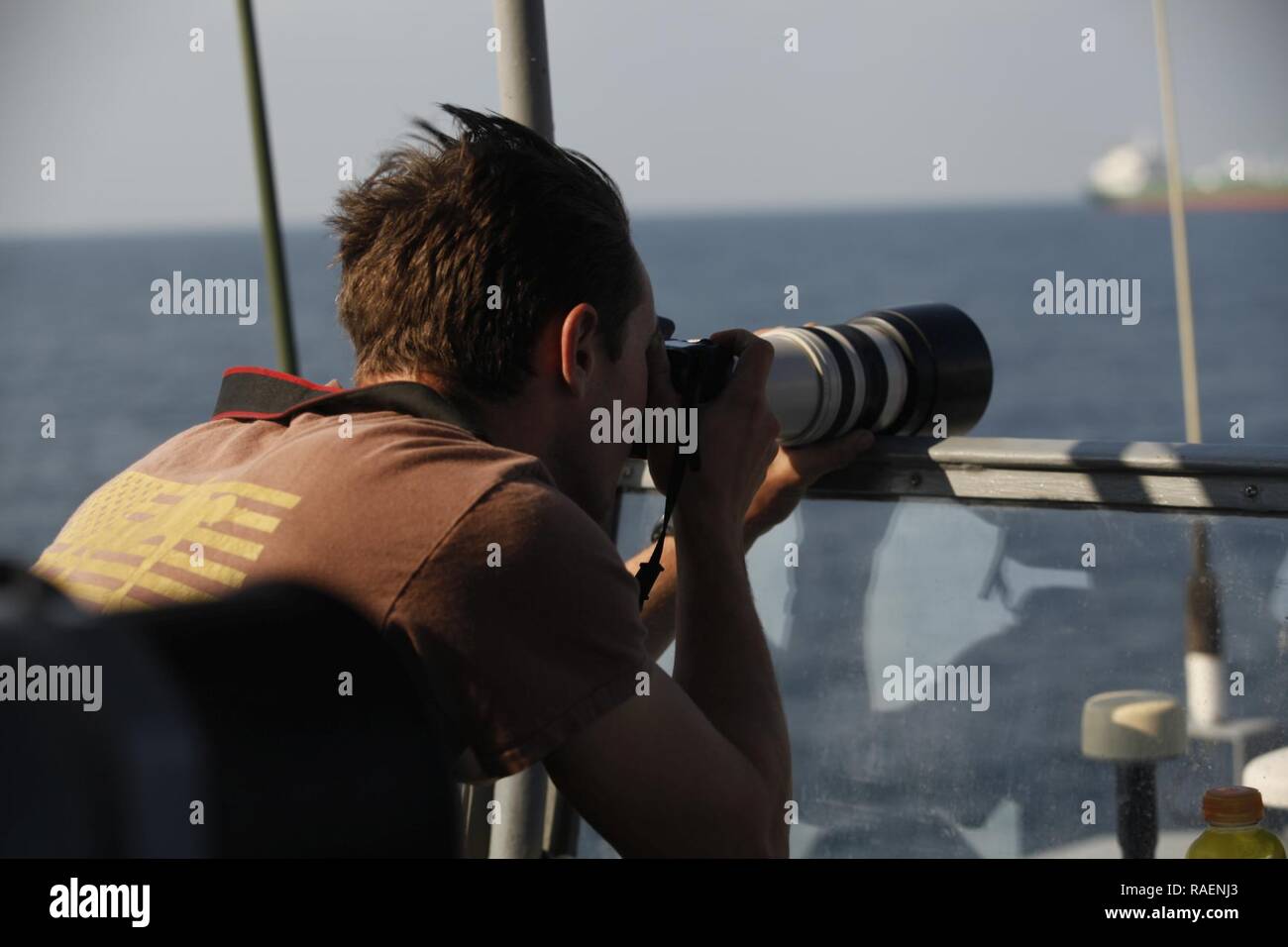 GULF OF OMAN (Dec. 14, 2018) A Sailor aboard the Cyclone-class coastal patrol ship USS Thunderbolt (PC 12) captures photographs of ship activity in the Gulf of Oman. Thunderbolt is deployed to the U.S. 5th Fleet area of operations in support of naval operations to ensure maritime stability and security in the Central Region, connecting the Mediterranean and the Pacific through the western Indian Ocean and three strategic choke points. Stock Photo