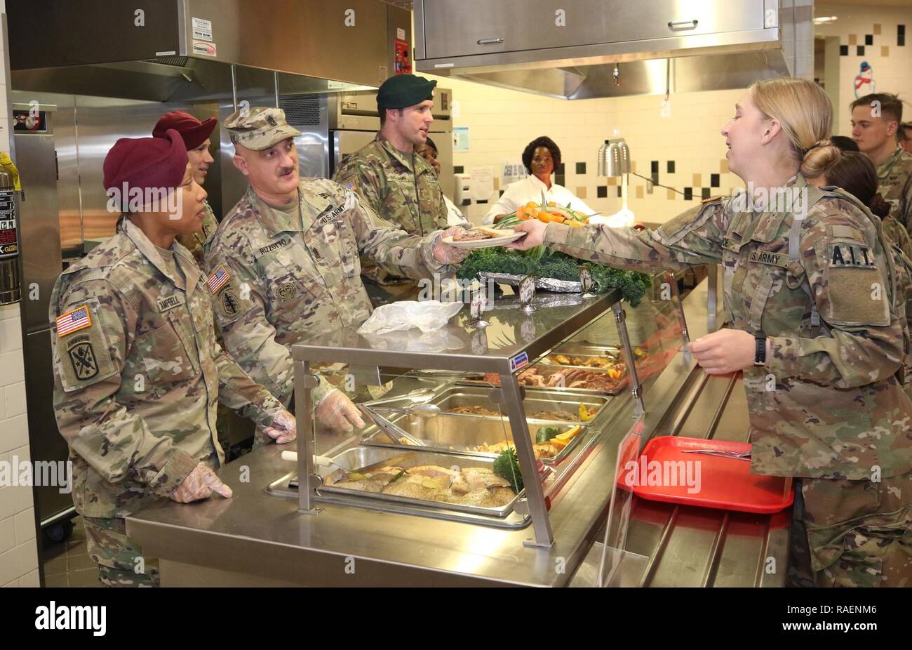 Major Natasha Campbell, executive officer, 3rd Battalion, 1st Special Warfare Training Group (Airborne), left, Command Sgt. Maj. Steve Rizzotto, command sergeant major, 3rd Battalion, 1st Special Warfare Training Group (Airborne), center, and Maj. Nick Williams, operations officer, Special Warfare Medical Group (Airborne) serves Soldiers during a holiday lunch at the U.S. Army Special Warfare Center and School Dining Facility, Fort Bragg, North Carolina, on Dec. 13, 2018. The DFAC personnel prepared a special lunch served by leadership prior to holiday leave. Stock Photo
