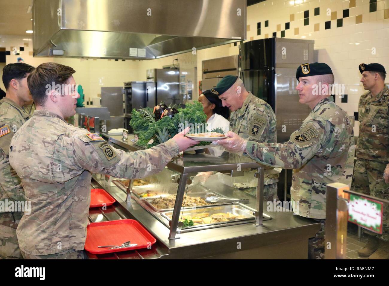 Sergeant Maj. Dale Kozelka, operations sergeant major, 4th Battalion, 1st Special Warfare Training Group (Airborne), hands a plate to a Soldier during a holiday lunch at the U.S. Army Special Warfare Center and School Dining Facility, Fort Bragg, North Carolina, on Dec. 13, 2018. The DFAC personnel prepared a special lunch served by leadership prior to holiday leave. Stock Photo