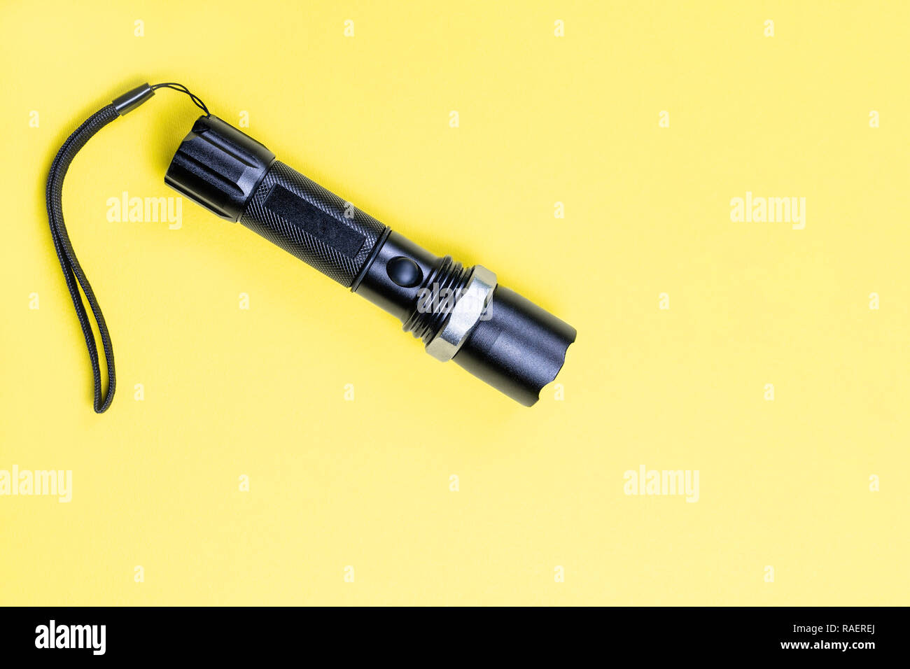 Blacc metal small tactical falshlight isoltaed on yellow background. Stock Photo