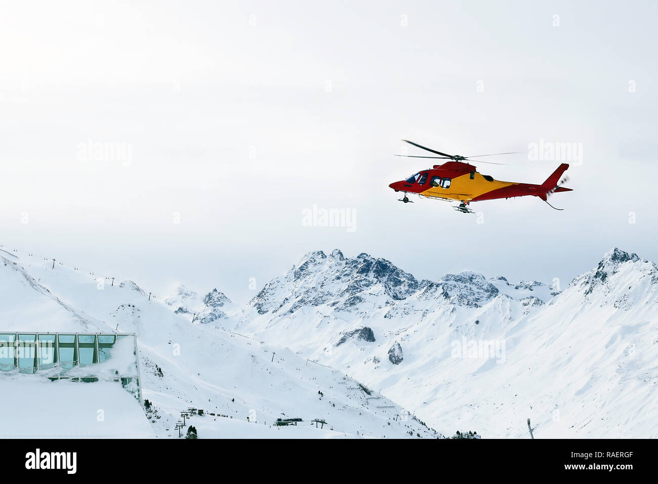 Rescue helicopter landing on slopes at ski resort in alpine mountains