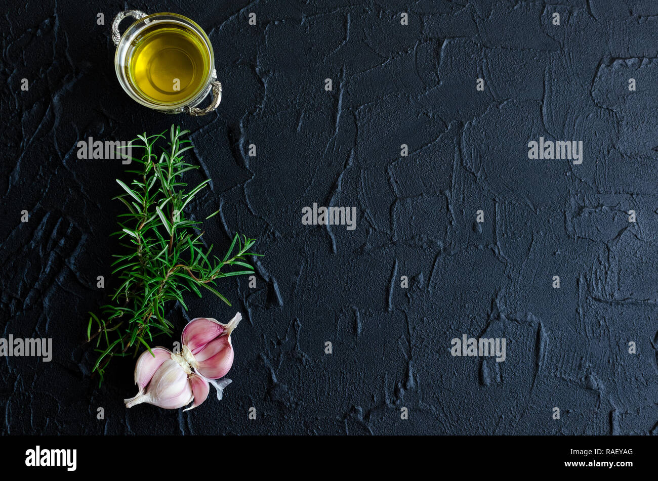 Rosemary, garlic and olive oil on dark stone table. Herbs and spices