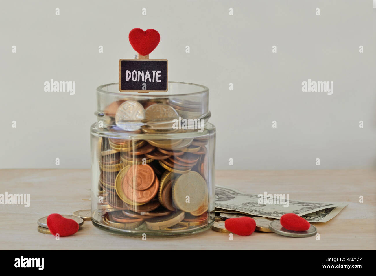 Money jar full of coins with Donate label and hearts - Charity concept Stock Photo