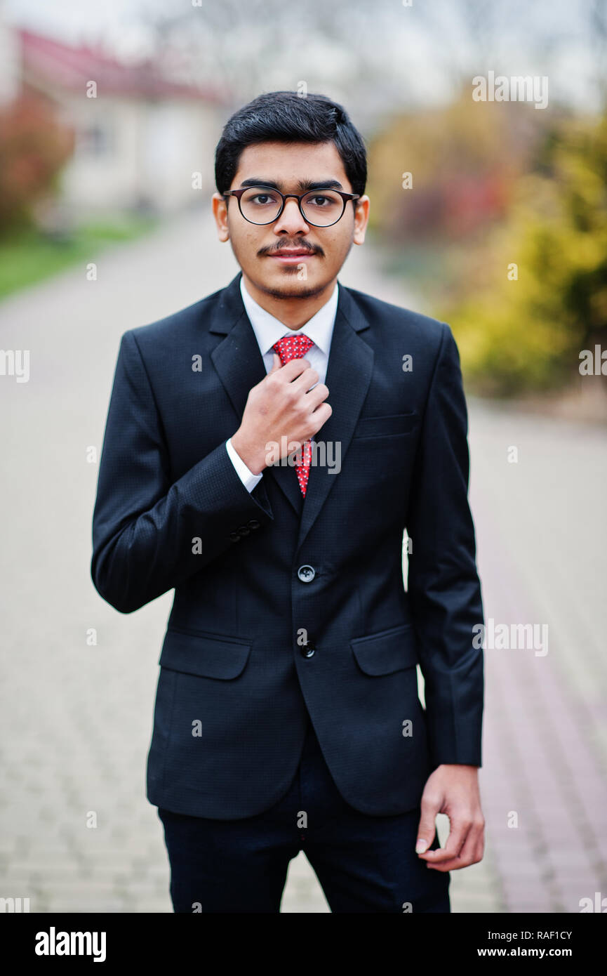 Indian young man at glasses, wear on black suit with red tie posed outdoor.  10340934 Stock Photo at Vecteezy