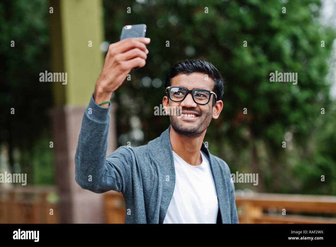 Stylish indian man at glasses wear casual posed outdoor and making selfie on phone. Stock Photo