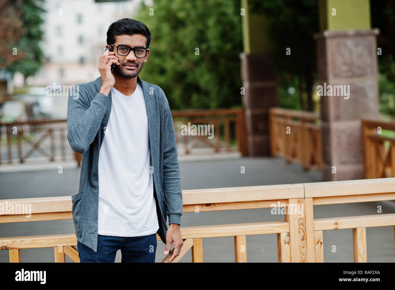 Stylish indian man at glasses wear casual posed outdoor and speaking on phone. Stock Photo
