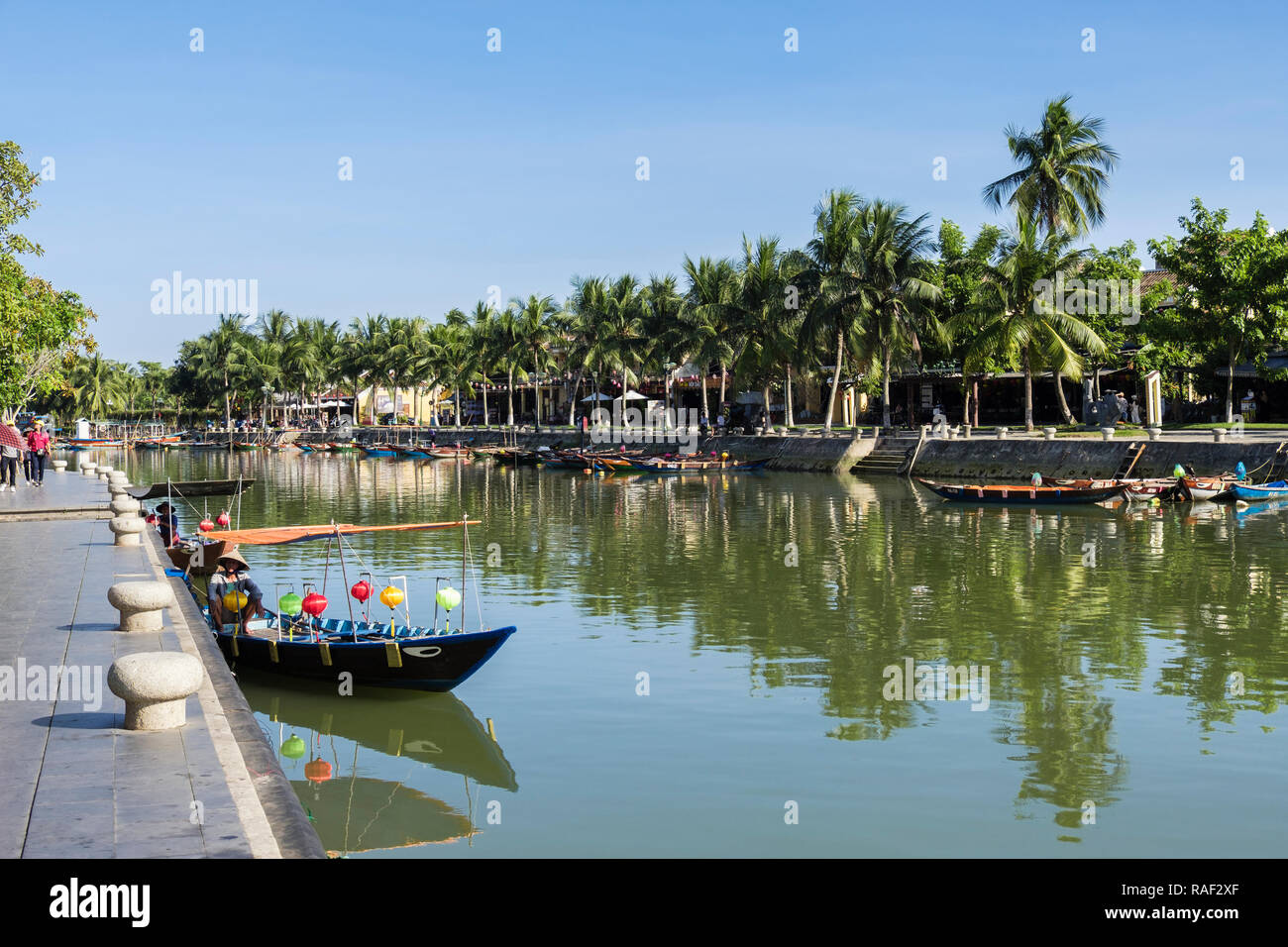 Traditional small boats on Thu Bon River lined with Palm trees in old quarter of historic town. Hoi An, Quang Nam, Vietnam, Asia Stock Photo