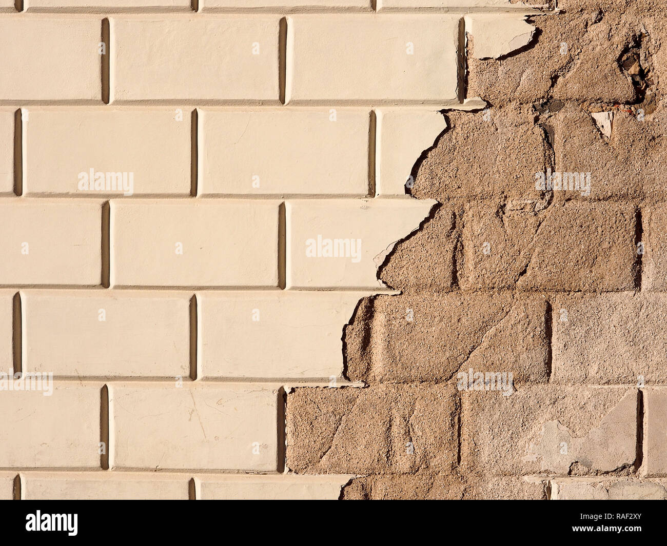 A portion of a wall made of bricks with removed plaster in the right side Stock Photo