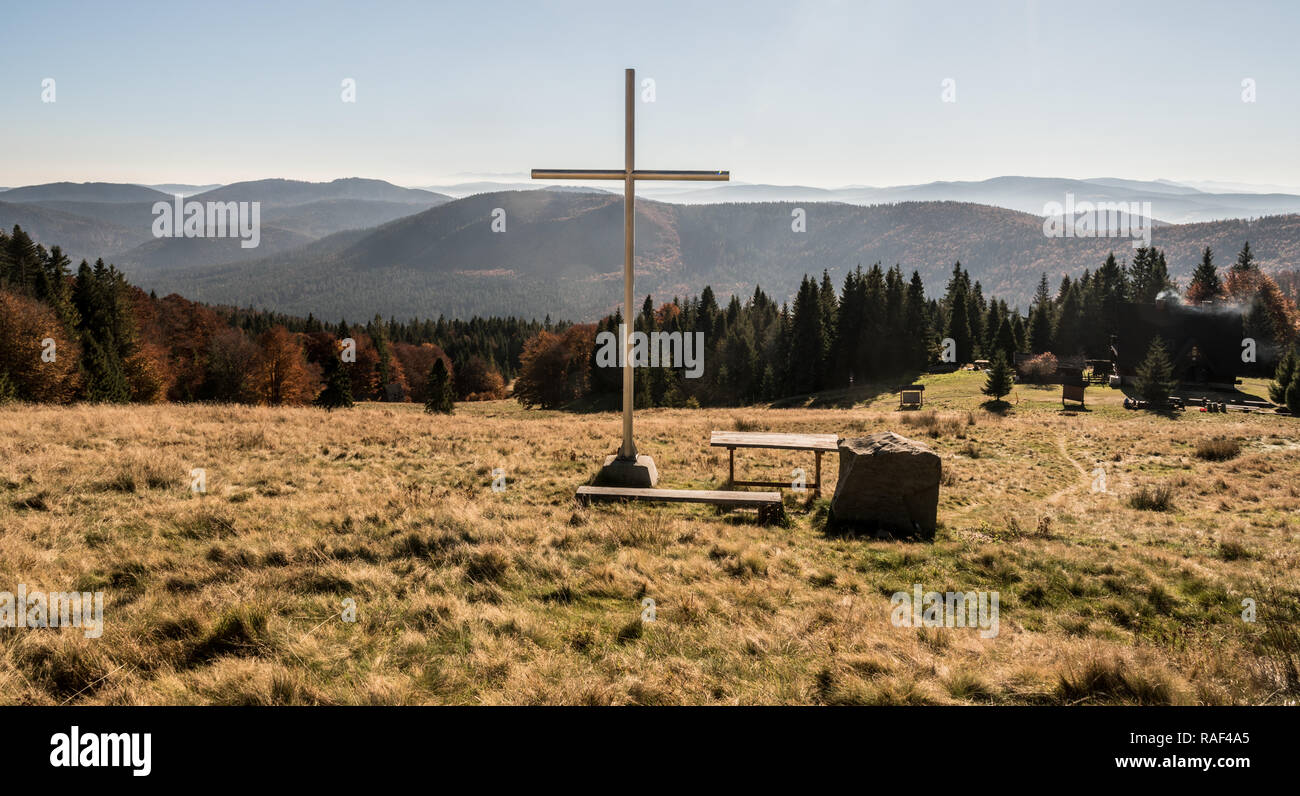 Hala Rycerzowa mountain meadow with colorful forest around, wooden cross, hut, hills on the background and clear sky in Beskid Zywiecki mountains in P Stock Photo