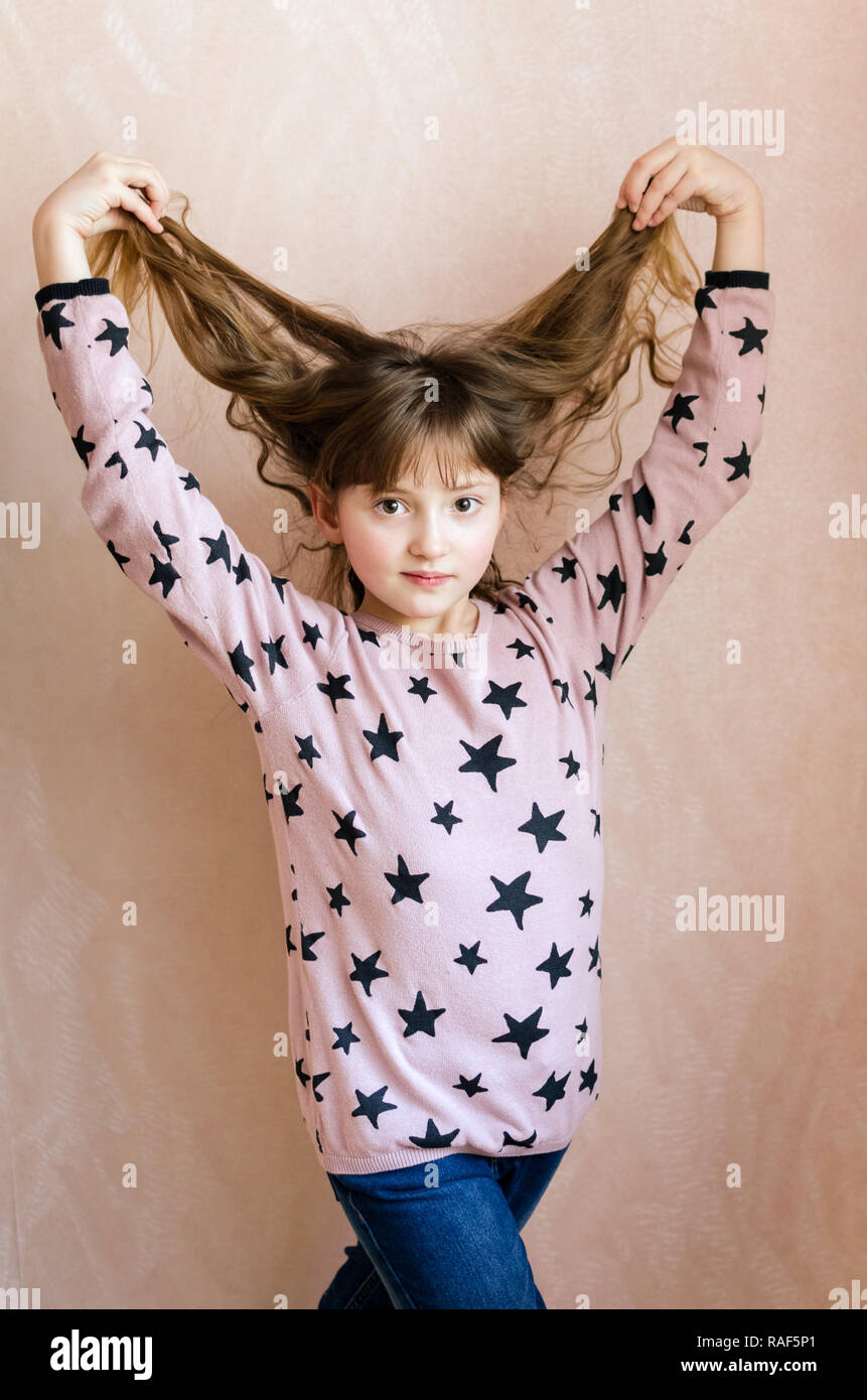 A little girl with long dark blonde hair and a cute smile on face loves ...