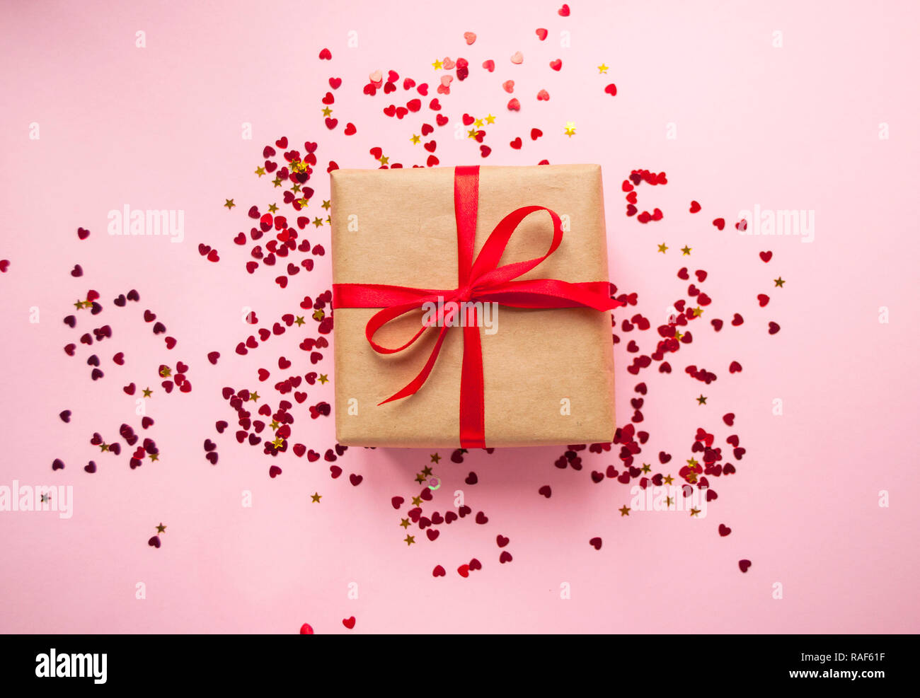 Gift box wrapped in brown colored craft paper and tied with red bow on ...