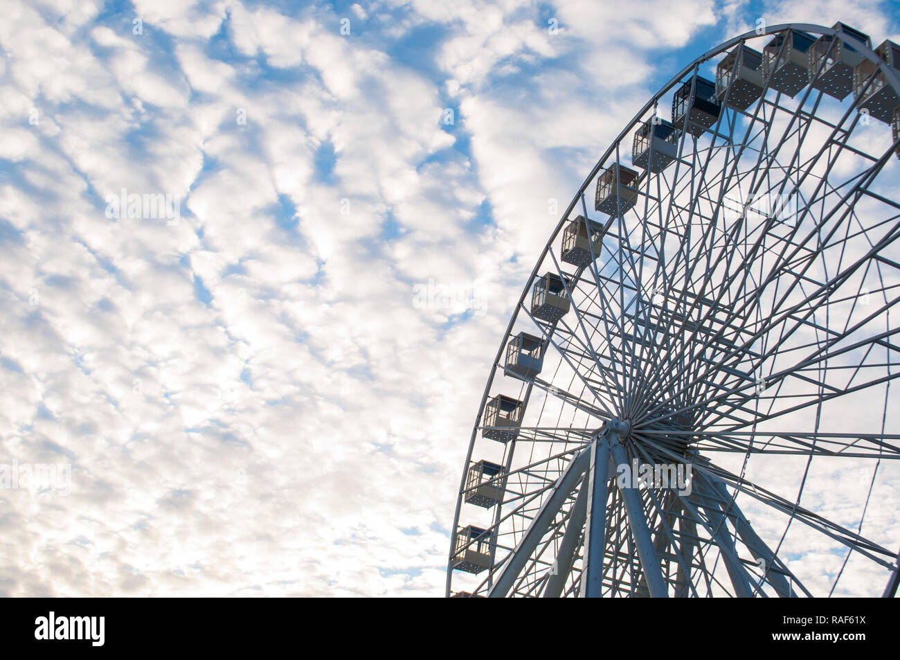 Part of ferris wheel over blue cloudy sky background in a fun park ...