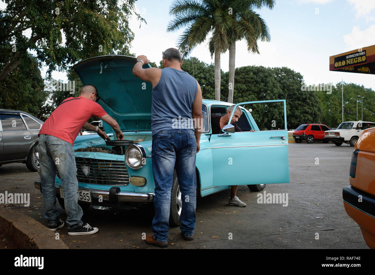 Man arranging a broken down car on a petrol station parking lot, Cuba Stock Photo