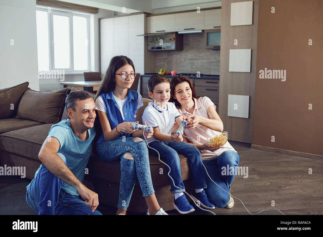 A cheerful family is playing video games in the house. Stock Photo