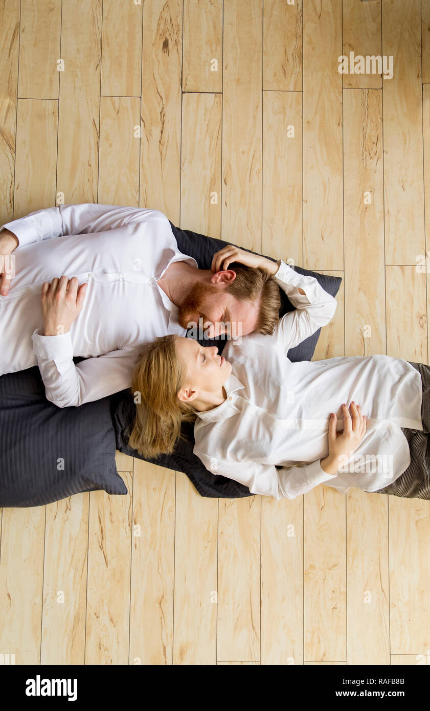 Loving young couple lying and kissing on the floor at home Stock Photo