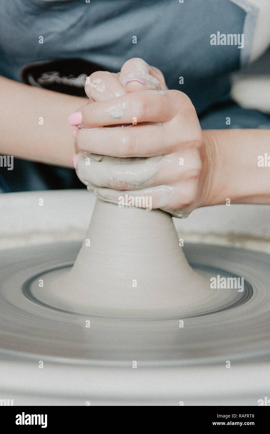 Creating a jar or vase of white clay closeup. Woman hands making clay