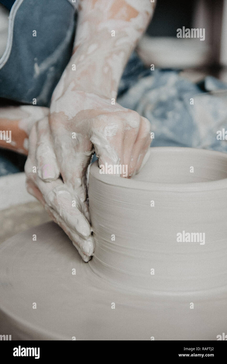 Creating a jar or vase of white clay closeup. Woman hands making clay