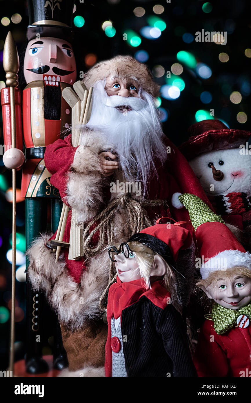 All dolls and puppets. Nutcracker Soldier, Santa, two elves  and Snowman, all together for a family picture. Christmas lights in the background. Stock Photo