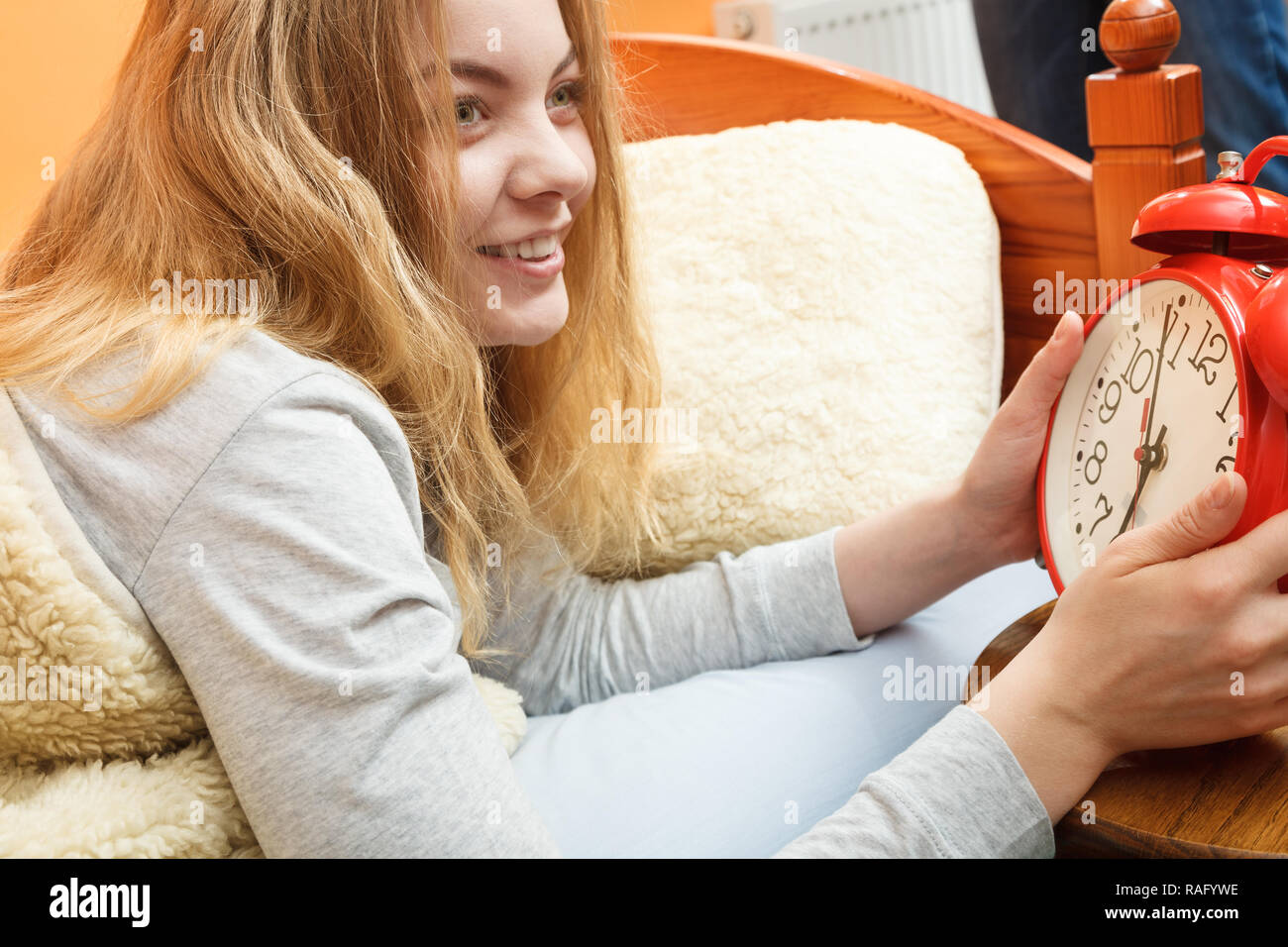 Happy woman waking up in bed turning off alarm clock. Young girl in the